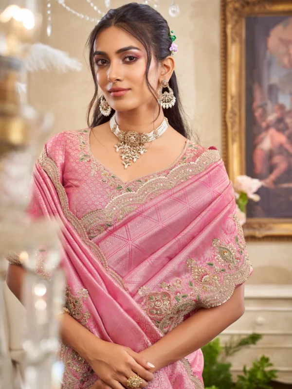Model posing in a magenta and green embroidered designer saree with heavy golden work on a staircase setting.