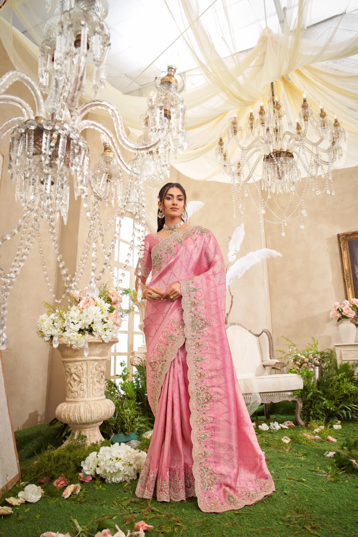 Model posing in a magenta and green embroidered designer saree with heavy golden work on a staircase setting.