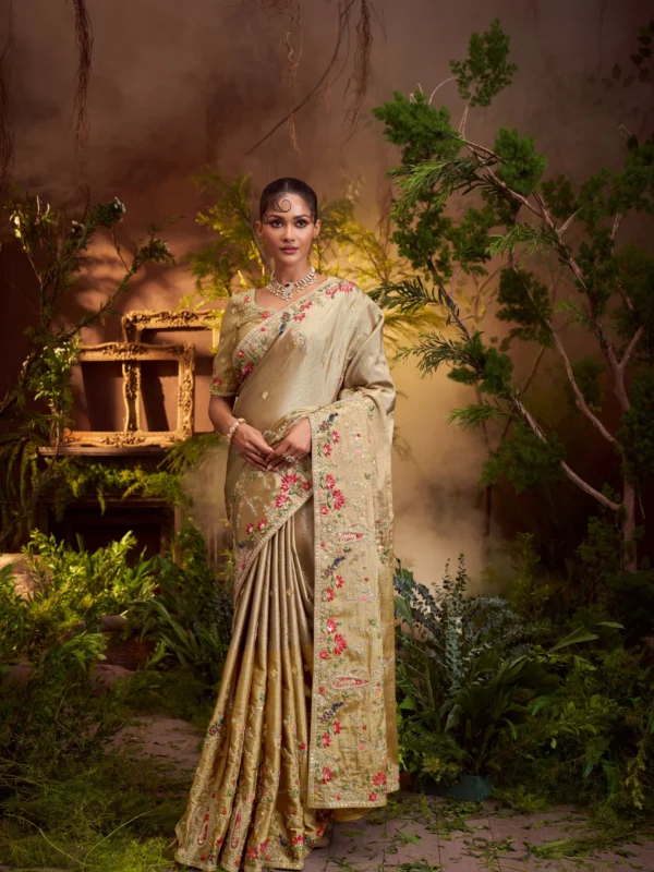 Model posing in an antique gold designer saree with multi-color floral and sequin embroidery, framed by a large ornate golden frame.