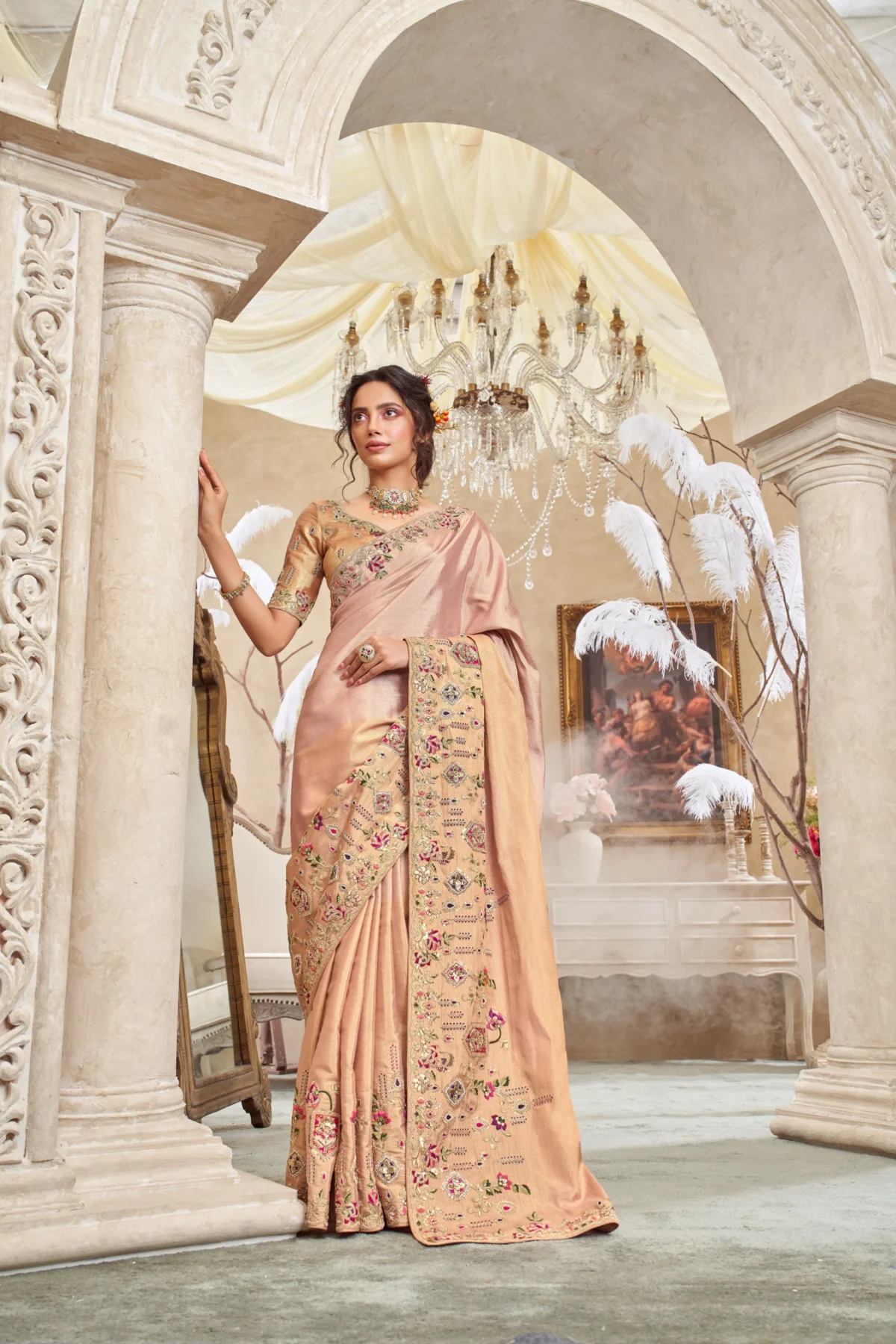 Model wearing a blush caramel hand-embroidered designer saree with ornate detailing and unstitched blouse.