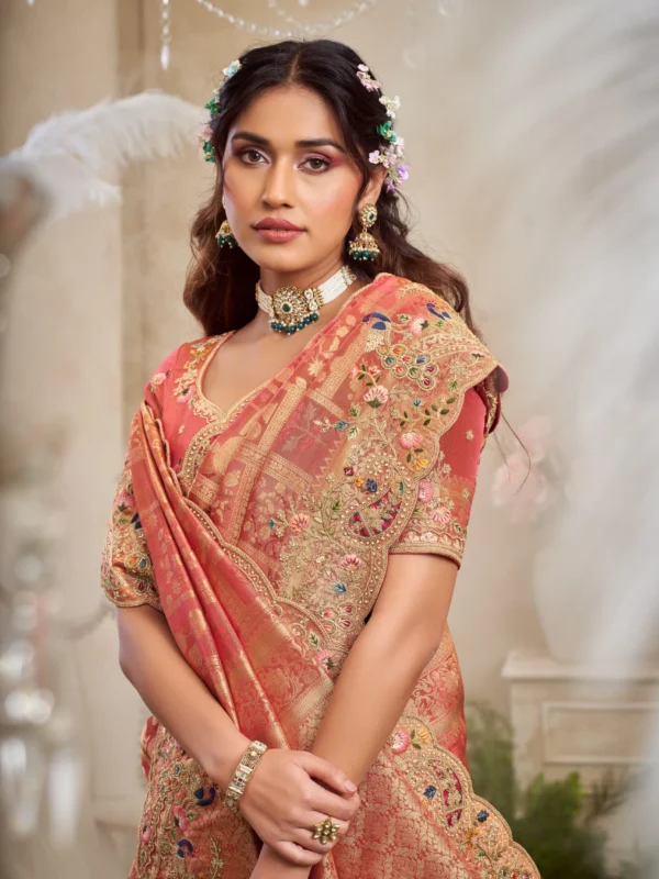 Model draped in a coral hand-embroidered luxury designer saree with heavy border and unstitched blouse.