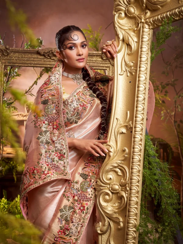 Model wearing a blush rose designer saree with heavy hand-embroidered border and matching embroidered unstitched blouse.
