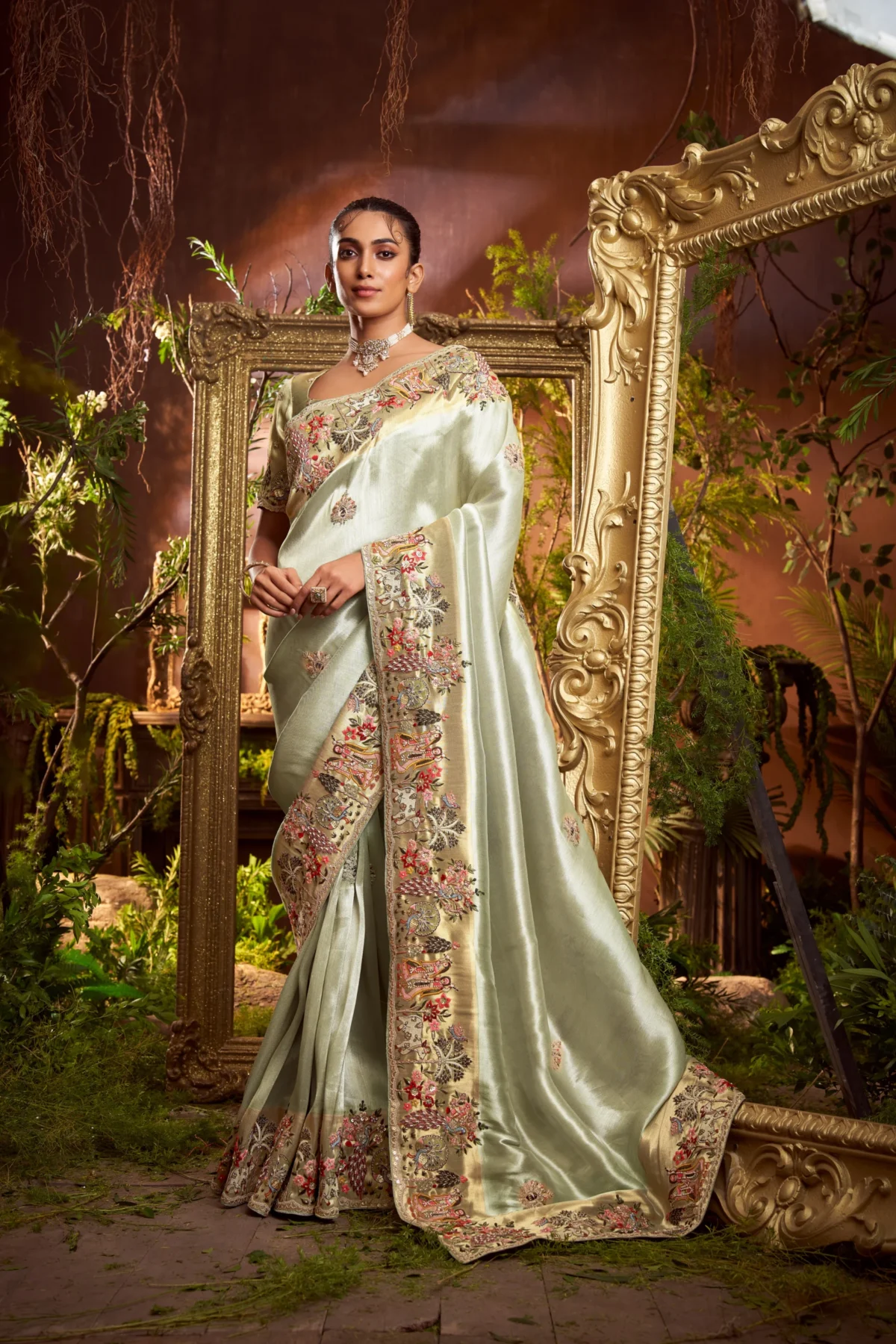 Model wearing a mint-gold designer saree with heavy embroidered border and matching embroidered unstitched blouse.