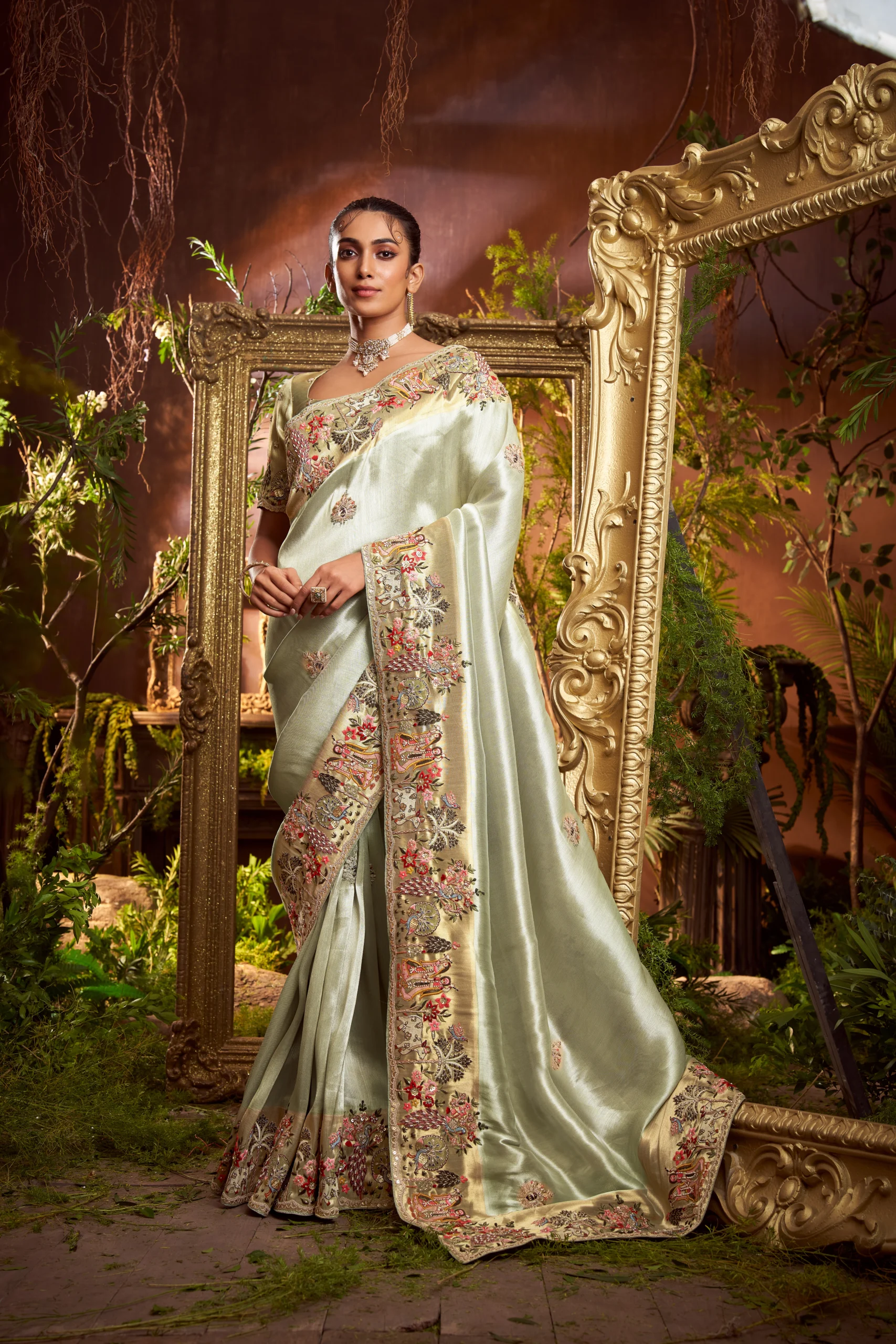 Model wearing a mint-gold designer saree with heavy embroidered border and matching embroidered unstitched blouse.
