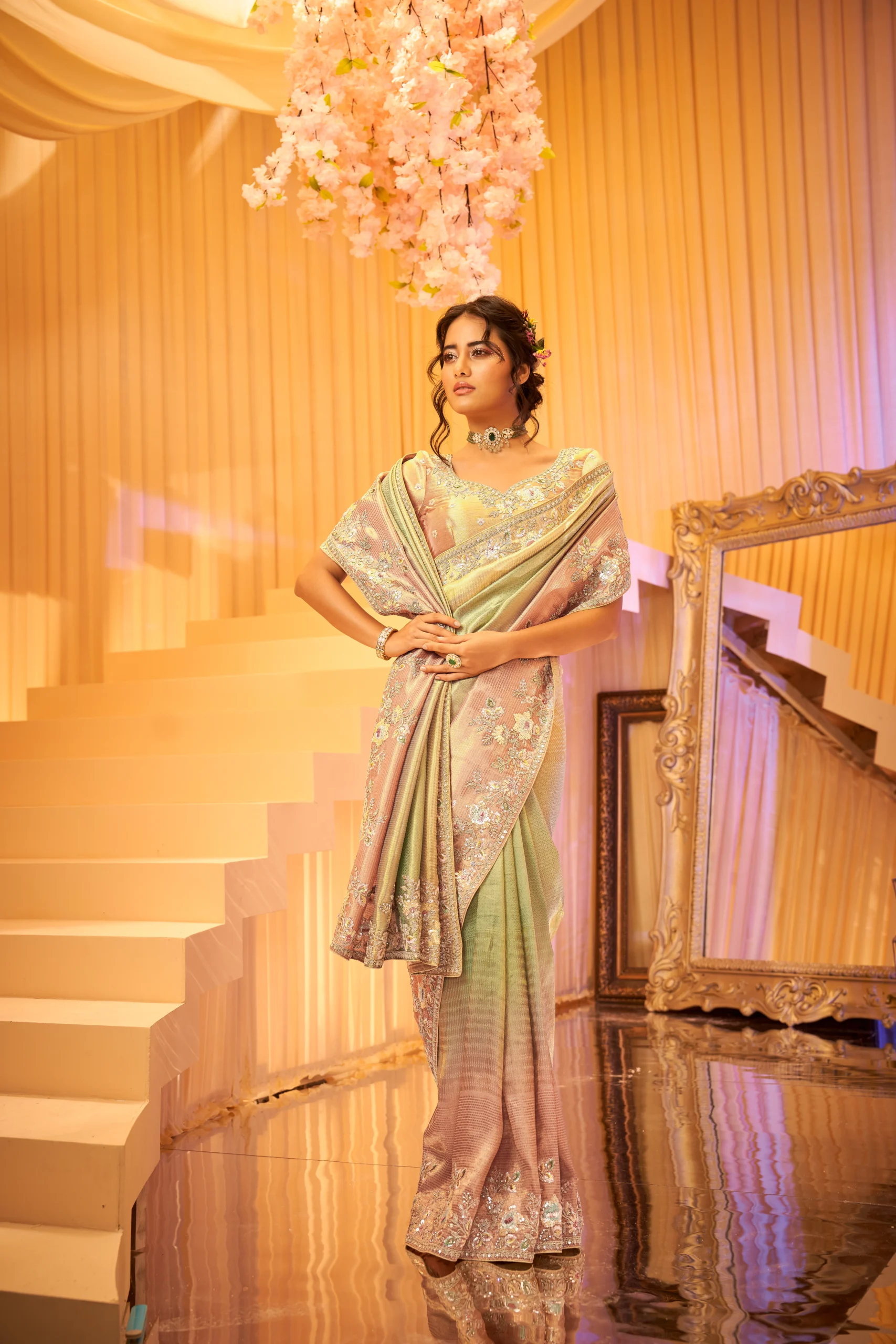 Model wearing a pastel ombre designer saree with heavy hand embroidery and matching embroidered unstitched blouse.
