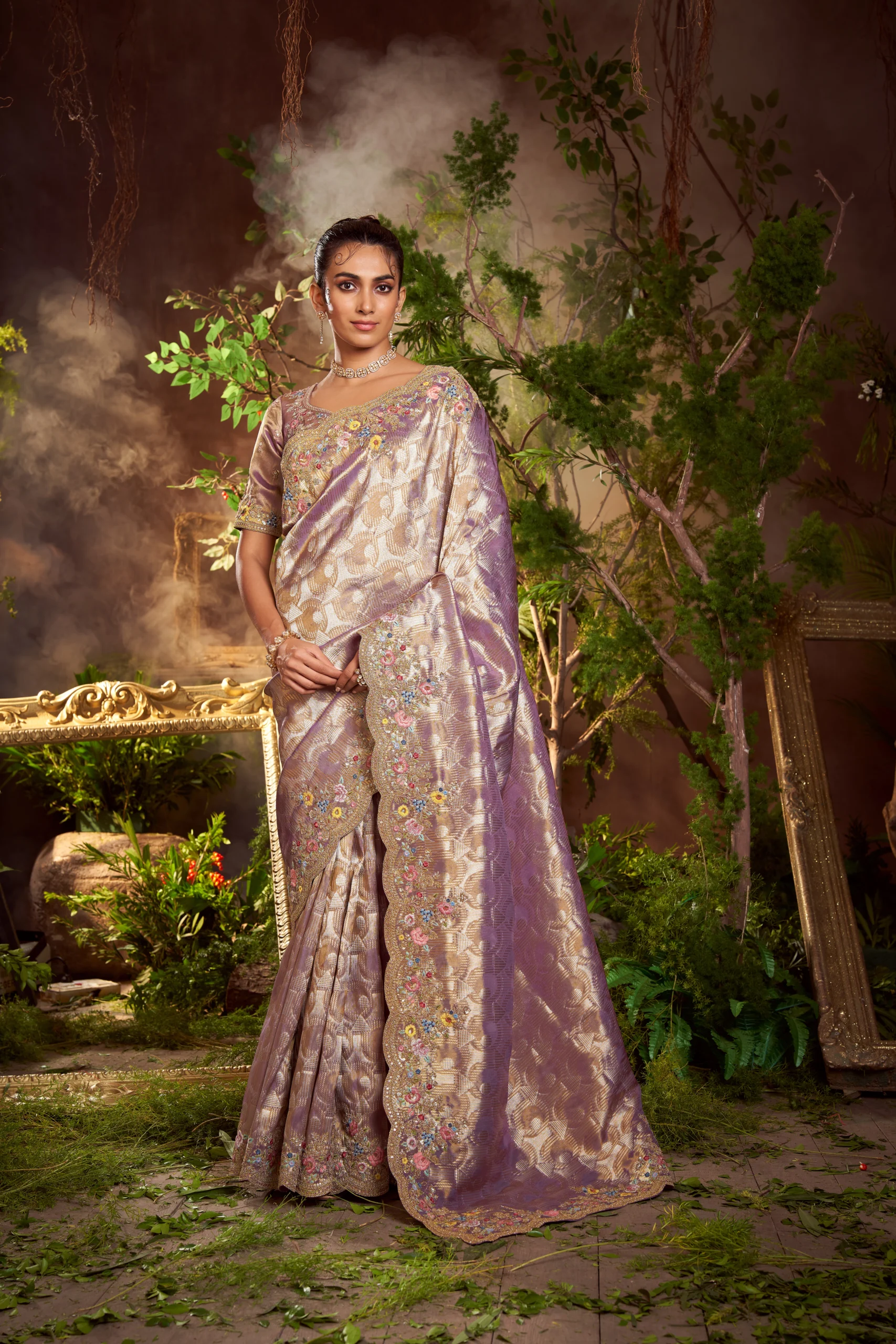 Model wearing a lavender-gold hand-embroidered silk brocade saree with scalloped floral border.