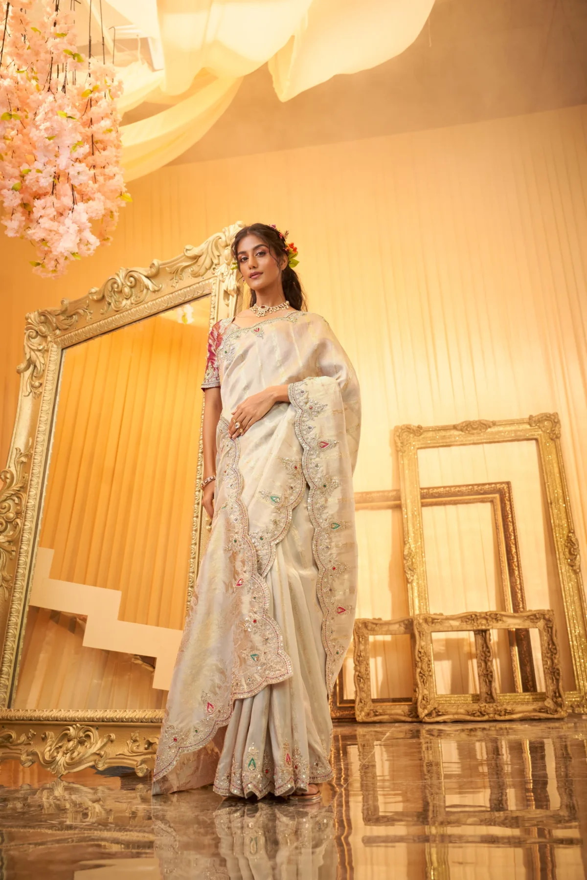 Model wearing an ivory scallop-embroidered luxury silk saree with intricate stone and threadwork.