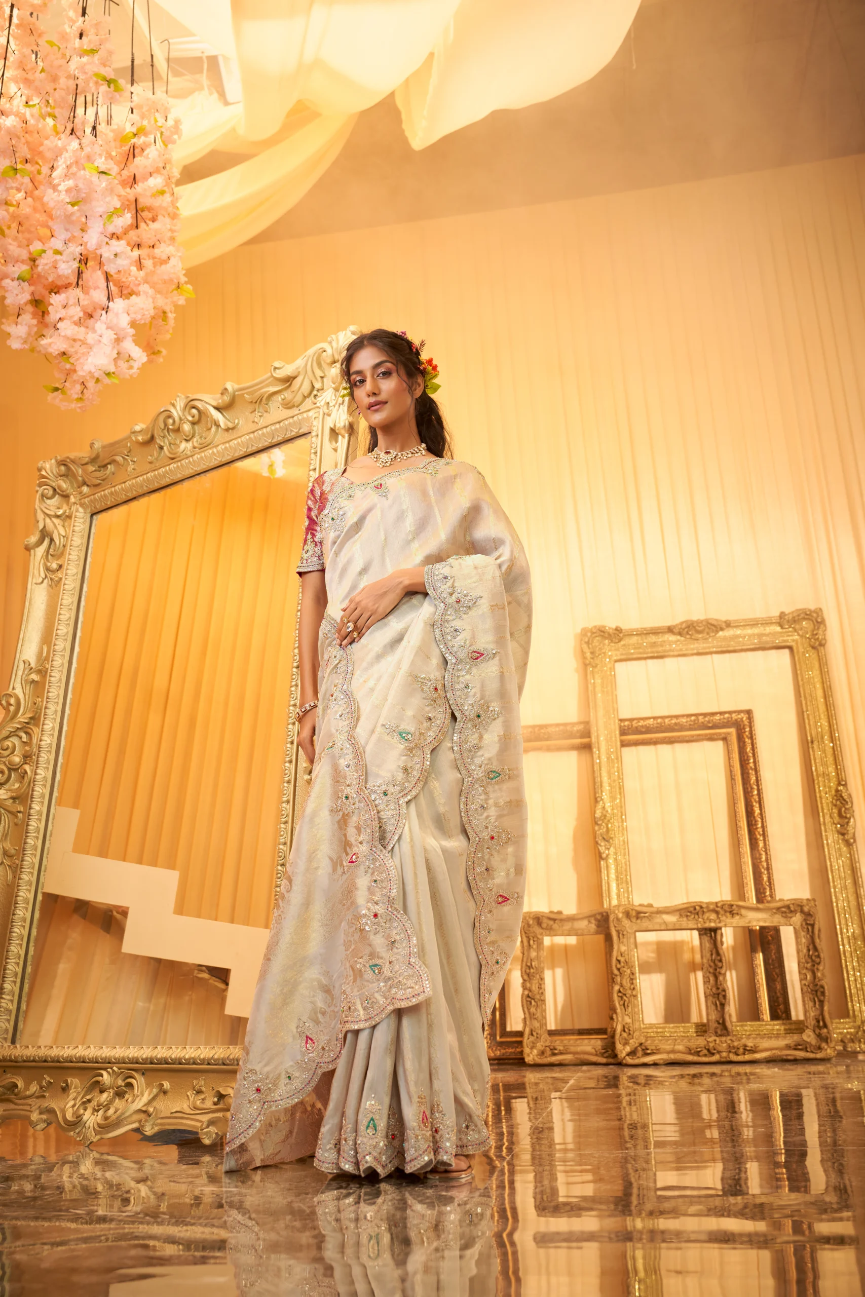 Model wearing an ivory scallop-embroidered luxury silk saree with intricate stone and threadwork.
