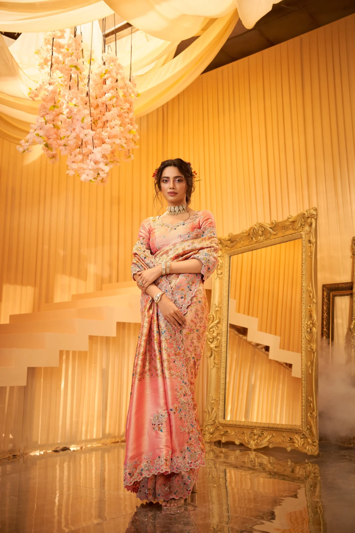 Model wearing a peach-pink hand-embroidered silk saree with scalloped embellished border.