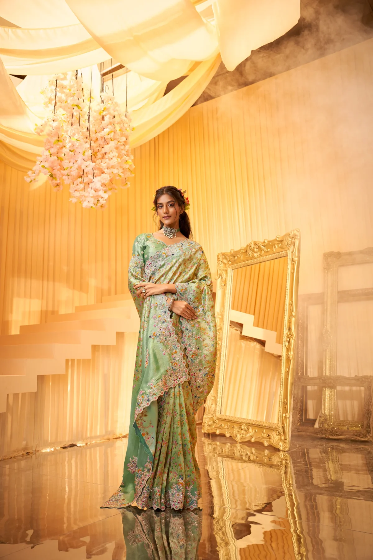 Model wearing mint-green hand-embroidered silk saree with scalloped embellished border.