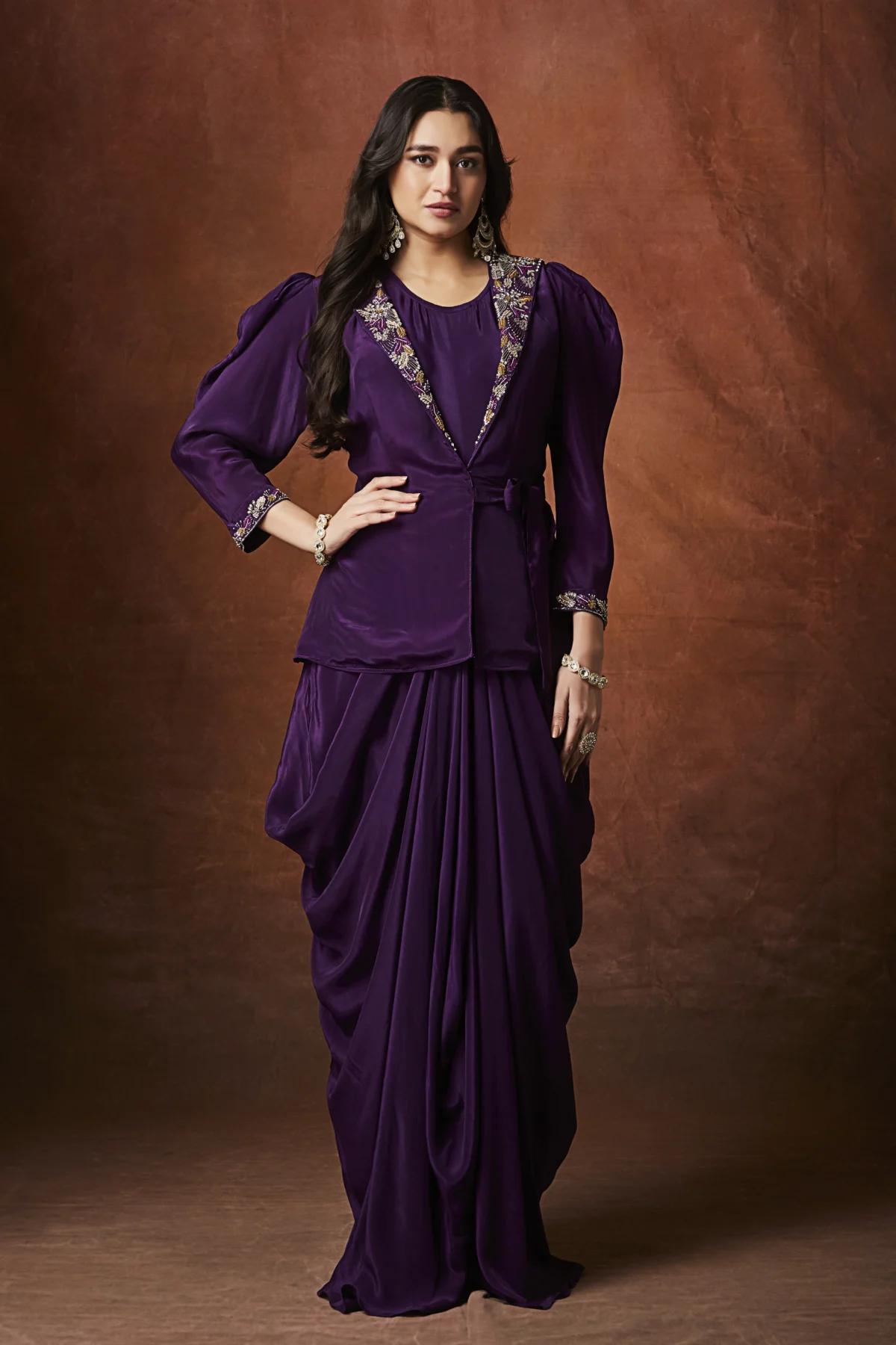 Purple draped Indo Western outfit with embellished wrap blouse and pleated flowing skirt for wedding reception wear.